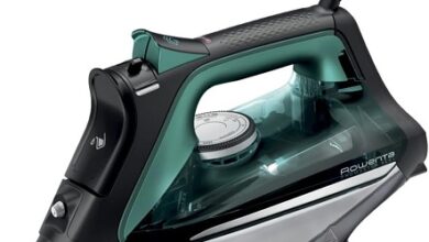 A black and green Rowenta Pro Master DW8360 steam iron with a stainless steel soleplate and a precision tip.